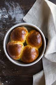 Four small dinner rolls on a baking sheet fresh out of the oven with a golden brown top